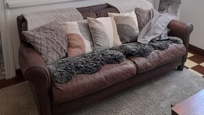 Ein gemütliches Wohnzimmer mit einer braunen Ledersofa, einem Wandbehang mit Muster und einem aufgehängten Hirschkopf.