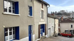 Ein Gebäude mit mehreren Fenstern und Türen, eine Kopfsteinpflasterstraße und ein rotes Auto, das dort geparkt ist.