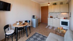 Un espacio habitable compacto con comedor, kitchenette y televisor montado en la pared.