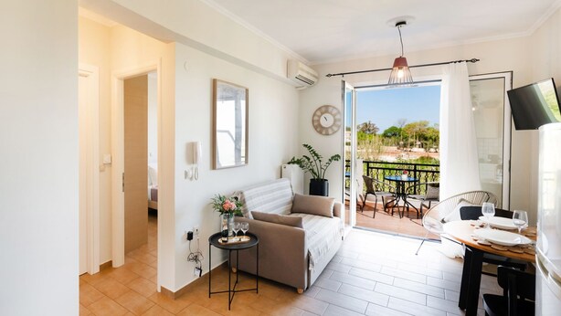 Una sala de estar moderna con un sofá, una mesita con una bandeja, una planta en maceta y vistas al exterior.