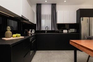 Eine moderne Küche mit schwarzen Schränken, einer Holz Arbeitsplatte und einem Edelstahl-Kühlschrank.