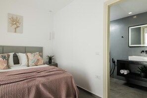 Ein Schlafzimmer mit Bett, Nachttisch und Beistelltisch mit Pflanze.