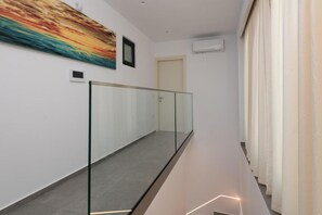Ein moderner Flur mit Glastrennwand, einem großen abstrakten Gemälde und einer Tür am Ende.