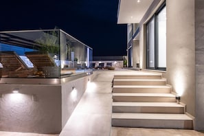 A modern outdoor staircase leading to a glass-enclosed area with plants and seating. - Villa Artemis in Zakynthos (Agios Sostis)