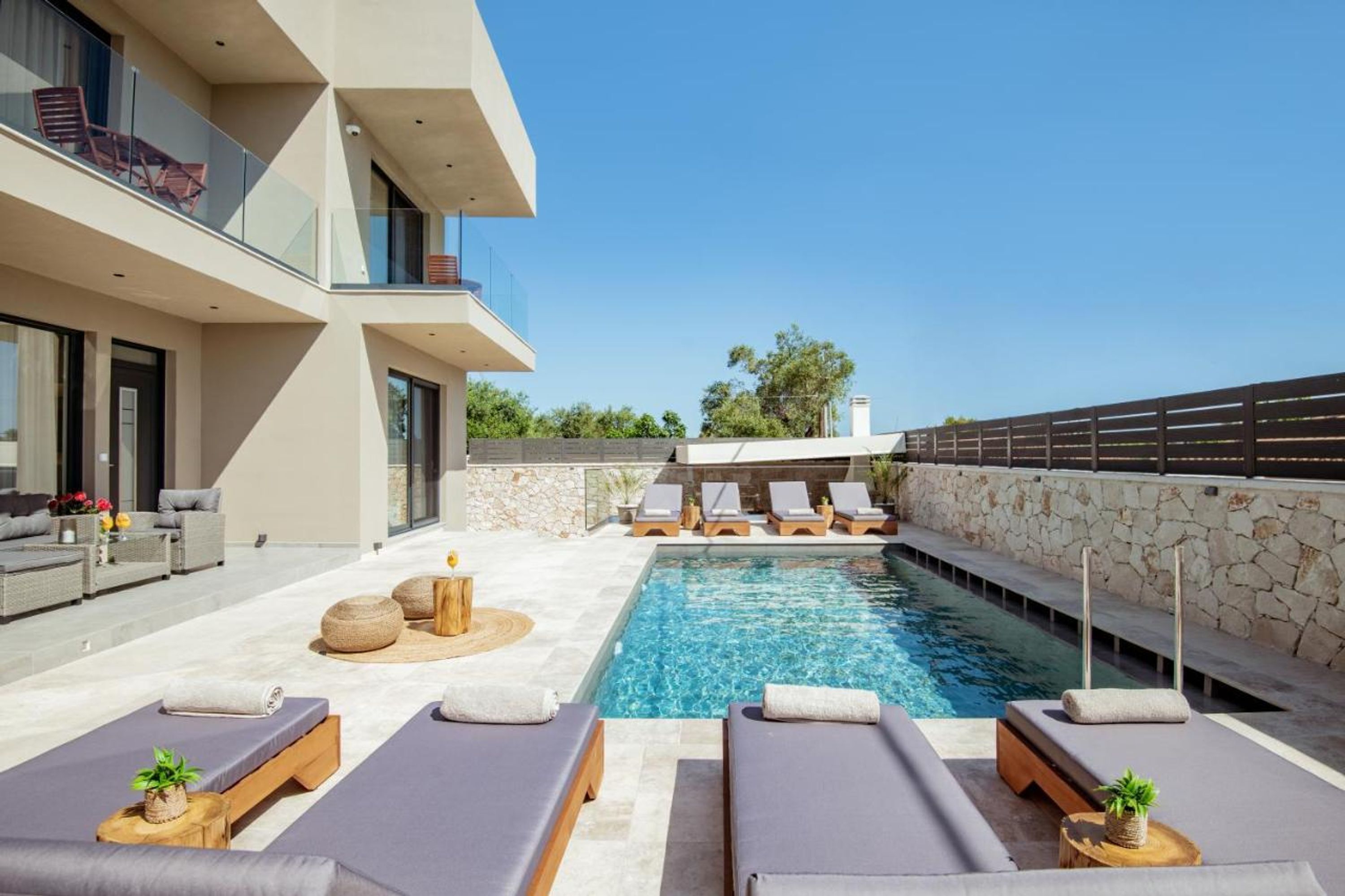 A modern outdoor pool area with lounge chairs and a stone wall.