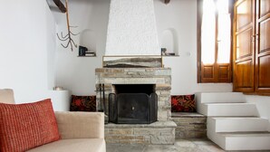 Ein Wohnzimmer mit Kamin aus Stein, einem beigen Sofa und einer Treppe, die in einen oberen Bereich führt.