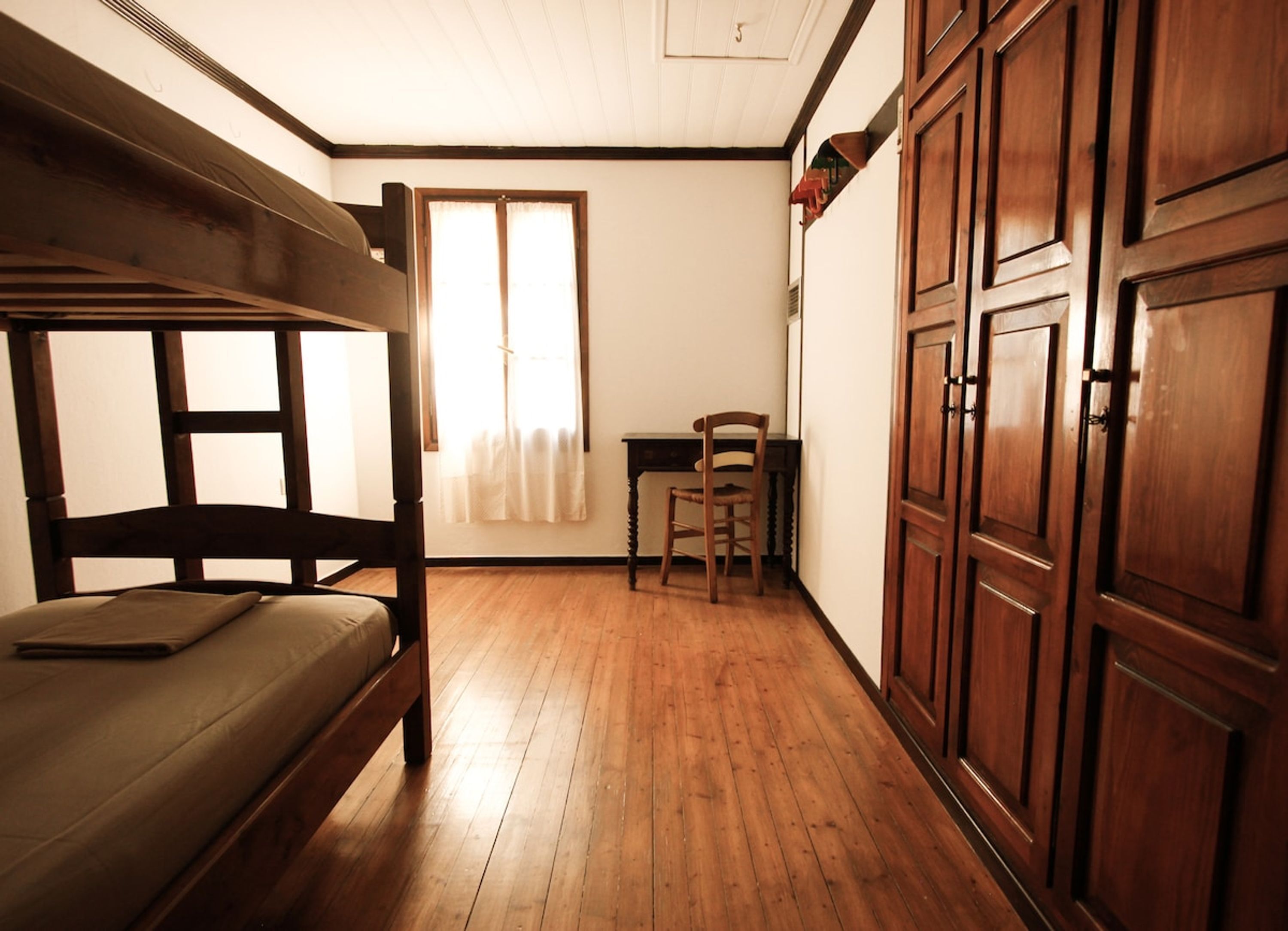 A room with a bunk bed, a desk, and a chair.