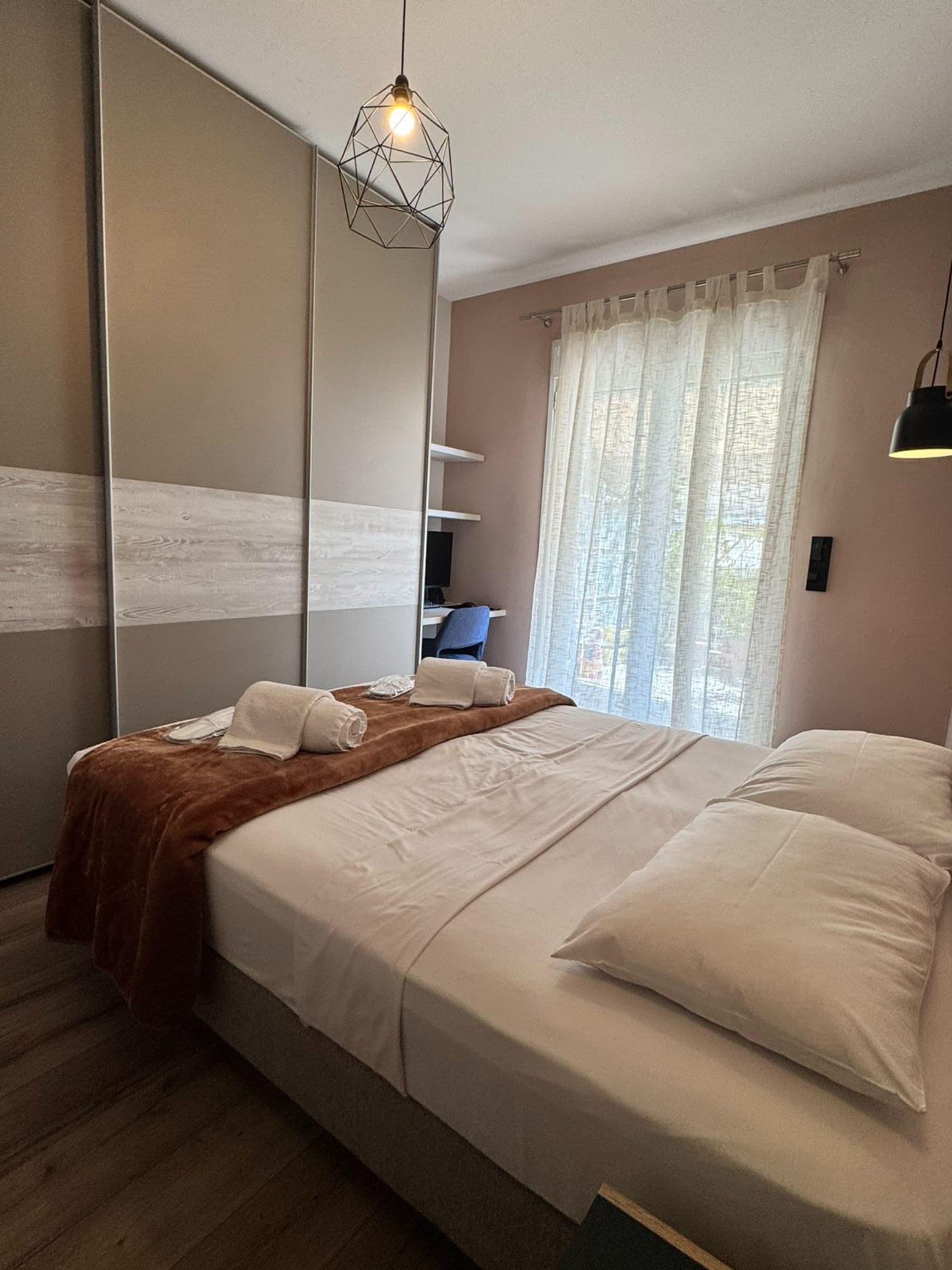 A modern bedroom with a large bed, a desk, and a chair.