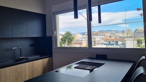 A modern kitchen with a large window, a black countertop, and wooden cabinets. - Athens Heart Acropolis Balcony (Athens)