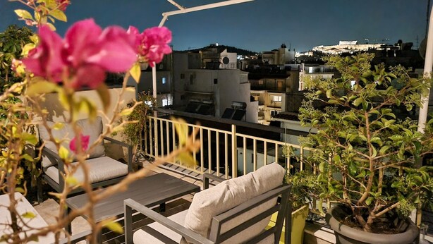 A rooftop terrace with outdoor seating, a railing, and potted plants. - Athens Heart Acropolis Balcony (Athens)