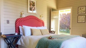 Een slaapkamer met een bed, nachtkastje, raam en deur.