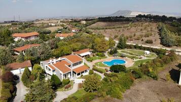 A residential area with houses, a swimming pool, and a mountainous backdrop.