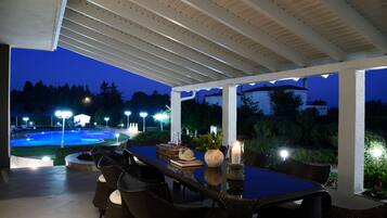 An outdoor patio with a pool, dining table, and chairs.