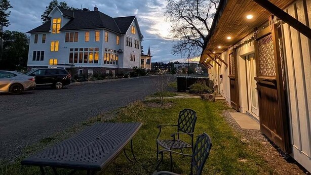 A two-story house with a porch, a table, and chairs outside. - Historic Horse Barn Apartment in Goshen (Goshen)