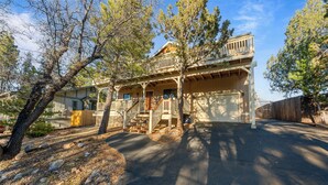 A two-story wooden house with a balcony, a covered porch, and a garage. - Beau Bear (Big Bear City)