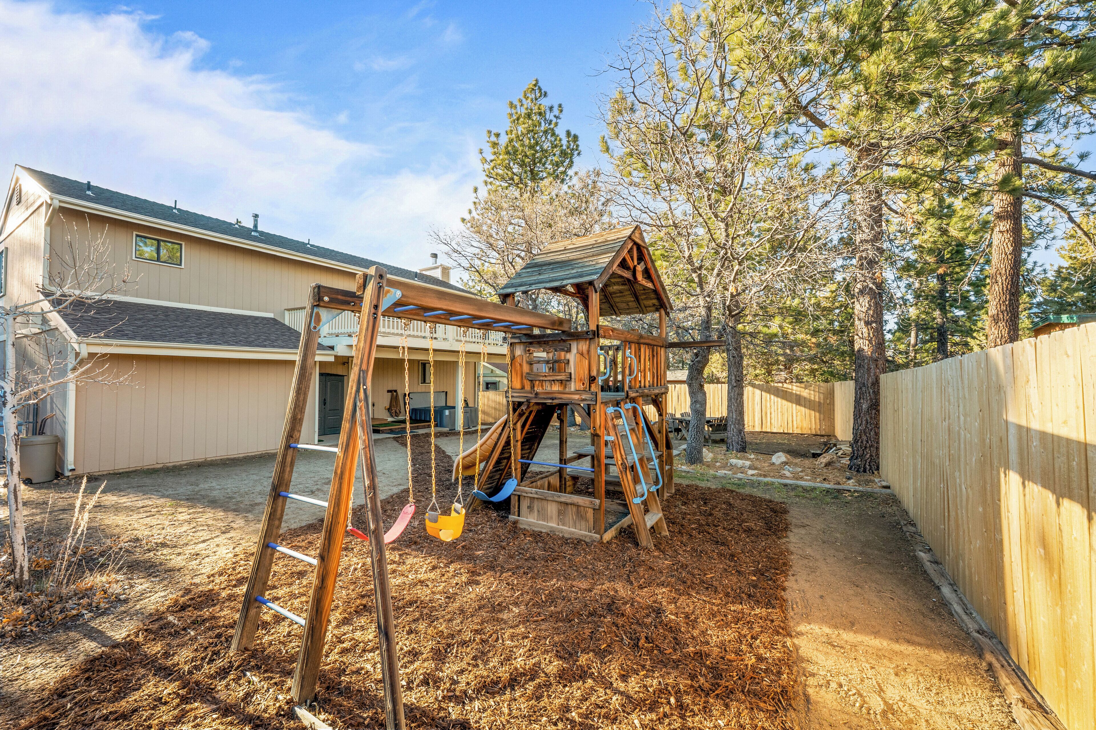 A wooden swing set in a backyard with a house in the background.