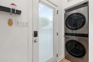 Ein Waschraum mit zwei Geräten für Frontlader, einer Tür mit satiniertem Glas, einem Lichtschalter und einem kleinen dekorativen Gegenstand an der Wand.