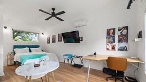 Una habitación moderna con cama, escritorio, silla y ventilador de techo.