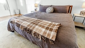 Ruime slaapkamer met een groot bed, nachtkastje met lamp en uitzicht op de omgeving.