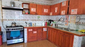 A kitchen with wooden cabinets, a gas stove, and a tiled backsplash. - Hostal Amigo Lucho  (San Pedro de Atacama)