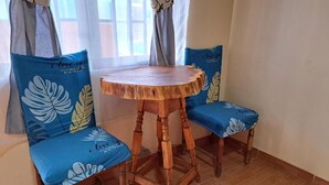 A dining area with a round wooden table and two blue chairs with leaf patterns. - Hostal Amigo Lucho  (San Pedro de Atacama)