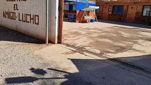 A hostel named "Hostal El Amigo Lucho" with a concrete exterior and a small structure with a blue roof. - Hostal Amigo Lucho  (San Pedro de Atacama)