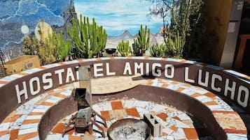 Uma área de estar externa circular com lareira, rodeada por um chão de mosaico e identificada como