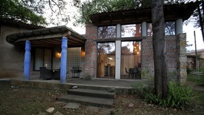 A building with a brick facade, large windows, and a covered outdoor seating area. - Maceiras House (San Cristóbal de las Casas)