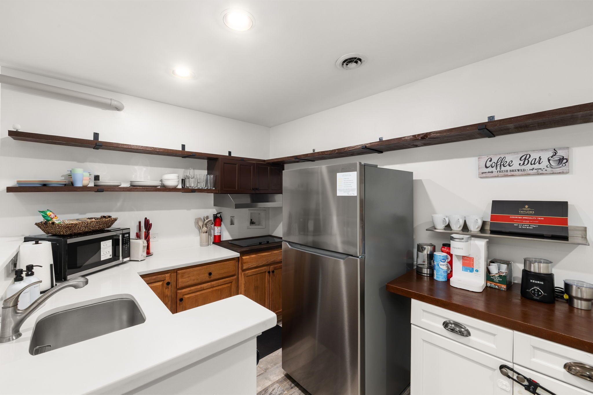 Una cocina moderna con electrodomésticos de acero inoxidable, armarios de madera y un letrero que indica barra de café.