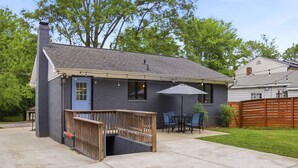 Une maison dotée d’un patio couvert, d’une terrasse en bois et d’une cour arrière clôturée.