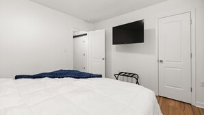 Une chambre à coucher avec un lit, un téléviseur fixé au mur et une porte donnant sur un placard.