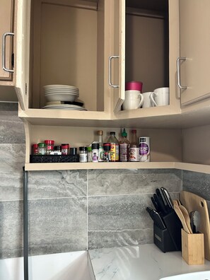 A kitchen with cabinets, a countertop, and various kitchen utensils. - Cozy 2-bedroom apartment in soothing Mangilao with AC (Mangilao)