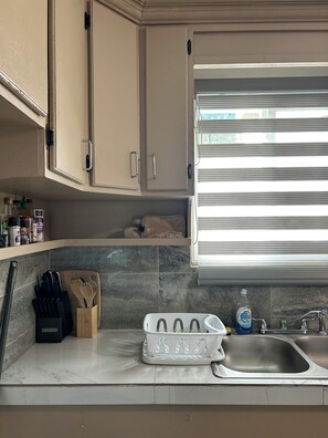 A kitchen with a marble countertop, a sink, and a window with blinds. - Cozy 2-bedroom apartment in soothing Mangilao with AC (Mangilao)