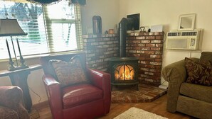 Una sala de estar acogedora con chimenea de ladrillo, sillón de cuero y sofá verde.