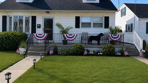 A two-story house with a front porch, a mailbox, and a dog statue.
