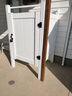 A white gate with black hinges and a wooden post.