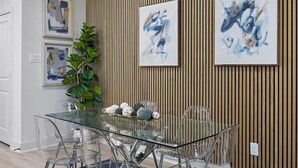 Un comedor moderno con una mesa de vidrio y sillas, rodeado de paneles de madera y arte abstracto.