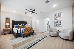 A modern bedroom with a large bed, a ceiling fan, and a view of the bathroom. - The Corinthian Retreat near NRG/Medical Center. Pets & long term stays welcome! (Houston)
