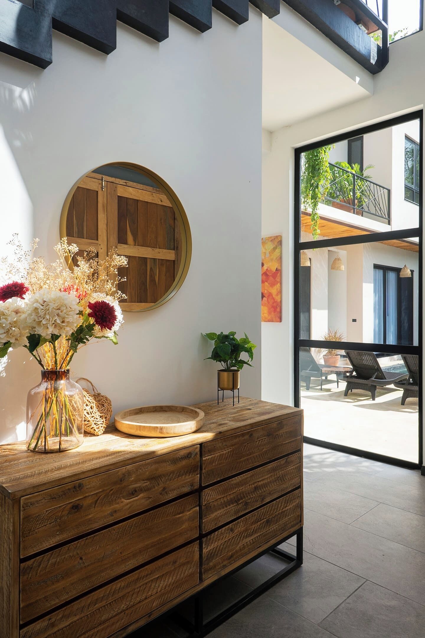 Een modern interieur met een houten kast, een ronde houten deur en een bloemenvaas.
