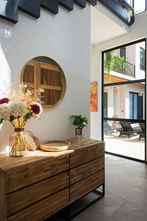 Un intérieur moderne avec un meuble en bois, une porte ronde en bois et un vase de fleurs.