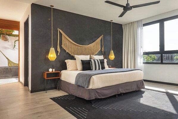 Une chambre moderne avec un grand lit, un ventilateur de plafond et une vue sur l’extérieur.
