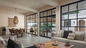 Un amplio espacio de sala con un gran ventanal, una mesa de comedor y un sofá.