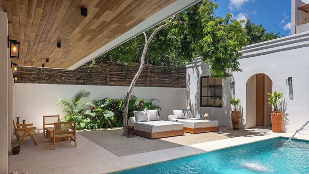 Zona junto a la piscina con techo de madera, mobiliario exterior y una piscina pequeña.