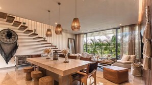 Ein modernes Wohnzimmer mit einem großen Holzesstisch, bequemen Sitzmöglichkeiten und einer Treppe mit integrierten Regalen.