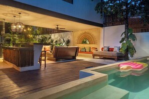 A modern outdoor living area with a pool, wooden deck, seating, and a bar area. - Villa Itze | 5Bdrm Jungle Oasis w/ Pool & BBQ<br>Dedicated concierge<br>Beach access (Tulum)