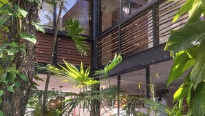 A modern building with a glass atrium surrounded by lush greenery. - Villa Itze | 5Bdrm Jungle Oasis w/ Pool & BBQ<br>Dedicated concierge<br>Beach access (Tulum)