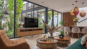 A modern living room with a large TV, round wooden coffee tables, and a green sofa. - Villa Itze | 5Bdrm Jungle Oasis w/ Pool & BBQ<br>Dedicated concierge<br>Beach access (Tulum)