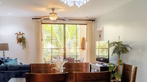 Un coin repas comprenant une table et des chaises, un ventilateur de plafond et une fenêtre avec des rideaux.