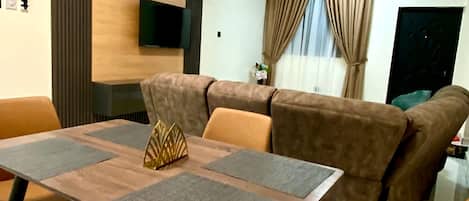 Una sala de estar moderna con comedor, un sofá, un televisor y un ventilador de techo.