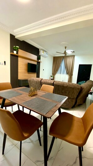Una sala de estar moderna con comedor, un sofá, un televisor y un ventilador de techo.